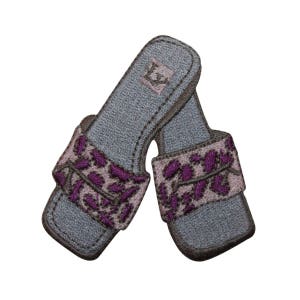 May include: A pair of gray embroidered slippers with a purple floral design. The slippers have a light gray strap with a white letter "L" on the top.