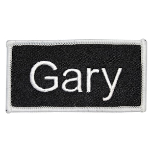 May include: Black rectangular name tag with white stitching around the edges. The name "Gary" is embroidered in white on the tag.