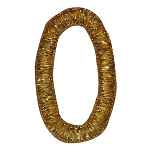 May include: A gold glitter number zero. The number is made of a thick, coiled wire covered in gold glitter.