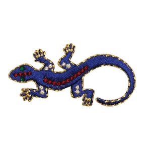 Könnte beinhalten: Blauer gestickter Gecko-Patch mit goldenen Verzierungen und roten und weißen Akzenten.