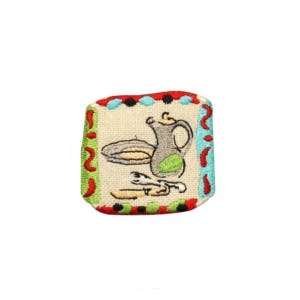 May include: Embroidered patch with a white background and a colorful border. The patch features a pitcher, a plate, and a knife and fork. The design is reminiscent of a kitchen or dining room.