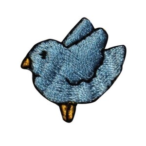 May include: A blue embroidered bird with a yellow beak and feet. The bird is perched on a branch and has its wings spread out.