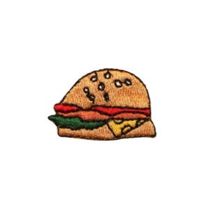 May include: A cartoon-style embroidered patch of a hamburger with a sesame seed bun, lettuce, tomato, and cheese.