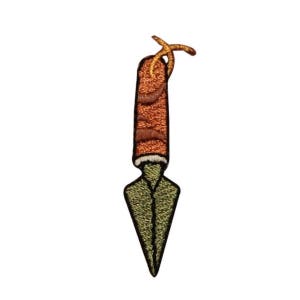 May include: An embroidered patch of a green and brown spear with a brown handle and a gold string tied around the top.