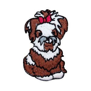 Può includere: Toppa ricamata da stirare con un cane marrone e bianco con un fiocco rosa. Il cane è seduto con la testa inclinata verso il basso.
