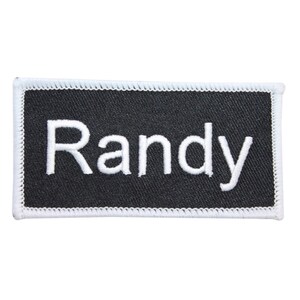 May include: Black name tag with white stitching around the edges. The name "Randy" is embroidered in white on the tag.