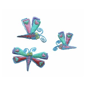 Può includere: Tre toppe ricamate da stirare con farfalle colorate con cuori rosa. Le farfalle sono in varie tonalità di blu, verde e rosa.