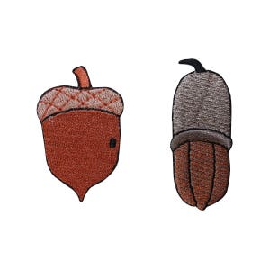 May include: Two embroidered acorn patches. One acorn is brown with a light brown cap and the other is brown with a gray cap.