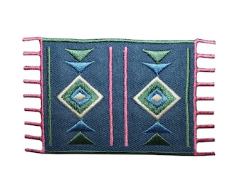 Op de afbeelding: Een blauwe en groene geborduurde patch met een geometrisch ontwerp. De patch heeft roze franjes aan de randen.