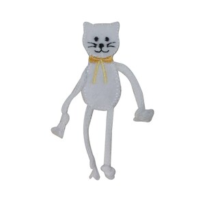 May include: White felt cat with black eyes and a yellow bow tie. The cat has long, thin arms and legs.