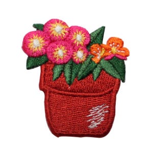 May include: A red flower pot with pink and orange flowers. The pot is filled with green leaves and the flowers have white centres.