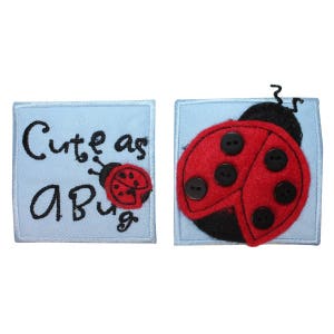 May include: Two blue fabric patches with embroidered ladybugs. One patch says "Cute as a Bug" and the other has a larger ladybug with black buttons for spots.