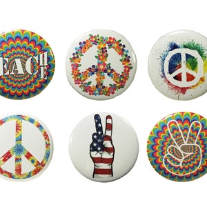 May include: Six round peace sign buttons with different designs. The designs include a peace sign with flowers, a peace sign with a tie-dye pattern, a peace sign with a rainbow swirl, a peace sign with a white background and rainbow splatter, a peace sign with a hand making the peace sign, and a peace sign with the word "Teach" in a rainbow swirl.