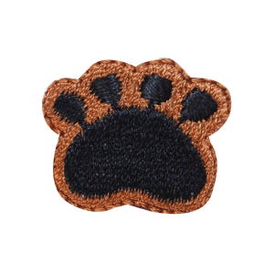 May include: A brown embroidered paw print with black stitching.