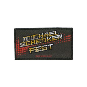 May include: A black embroidered patch with the text "MICHAEL SCHENKER FEST" in white, gold, and red lettering. The text is stylized and appears to be in a futuristic font. The patch also features a red and white pixelated design in the background. The text "©2016 NUCLEAR BLAST" is printed in red at the bottom of the patch.