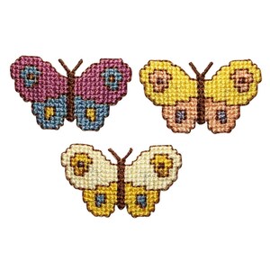 May include: Three embroidered butterfly patches in pink, yellow, and cream colors. The butterflies have brown accents and are stitched with a cross-stitch pattern.