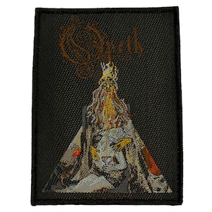 May include: Black rectangular patch featuring the band name "Opeth" in a stylized, ornate font. The patch depicts a detailed illustration of a figure with a crown and flowing robes in shades of gold, white, and red.