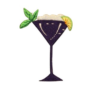 May include: Purple martini glass with a white foamy drink, a green lime wedge, and a green sprig of mint.