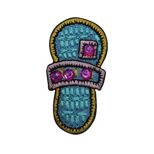 May include: A blue and gold embroidered patch shaped like a slipper with pink rhinestones.