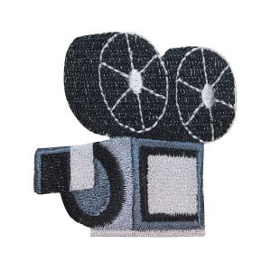 May include: A black and white embroidered patch of a vintage movie camera. The camera has two large spools and a rectangular viewfinder.
