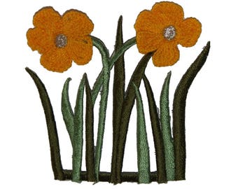 May include: An embroidered patch featuring two yellow flowers with green stems and leaves. The flowers have a simple design and are outlined in a darker yellow.