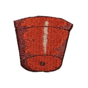 May include: A brown embroidered patch shaped like a flower pot with a white stem and a brown circle in the centre.