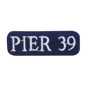 May include: A navy blue rectangular patch with white embroidered text that reads "PIER 39".