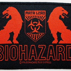 May include: Black embroidered patch with a red biohazard symbol, two red lion figures, and the text "MATA LEAO" and "BIOHAZARD" with a copyright notice.