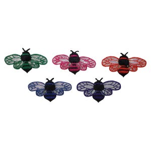 May include: Five embroidered iron-on patches of bees in different colors: green, pink, blue, purple, and red. Each bee has black and white stripes and a black head.
