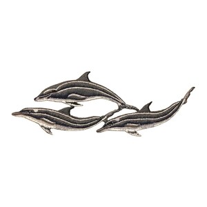 Peut inclure: Trois dauphins rayés de noir et blanc nageant en ligne. Les dauphins sont brodés sur un fond blanc.