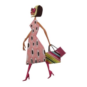 May include: Embroidered iron-on patch of a woman in a pink dress with black and white polka dots, wearing sunglasses and carrying a colorful striped bag.