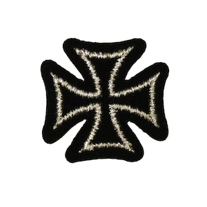 May include: Black Iron Cross patch with silver metallic thread outlining the cross shape. The patch has a thick, black border. The Iron Cross is a military decoration originating in Prussia, and is still used today.