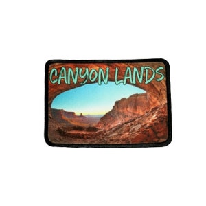 May include: A black and white patch with a photo of a canyon landscape and the text "CANYON LANDS" in green.
