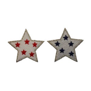 May include: Two white fabric star-shaped patches with gold stitching. One patch has five red stars and the other has five navy blue stars.