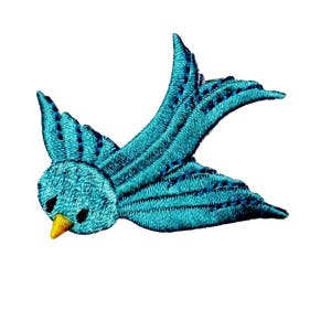 May include: A turquoise blue embroidered bird with a yellow beak, flying with its wings spread out.