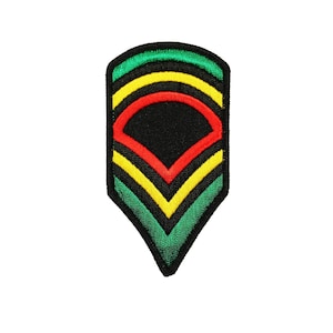 May include: A green, yellow, and red embroidered patch in the shape of a chevron. The patch has a black diamond shape in the center.