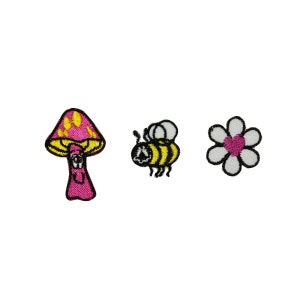 May include: Three embroidered iron-on patches: a pink mushroom with yellow spots, a yellow and black bee, and a white flower with a pink heart in the center.