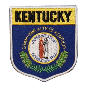 May include: An embroidered patch featuring the state seal of Kentucky. The seal depicts a couple standing together with the words "United We Stand, Divided We Fall" around them. The words "Commonwealth of Kentucky" are written around the seal. The patch has a blue background with a yellow border and the word "Kentucky" in black letters at the top.