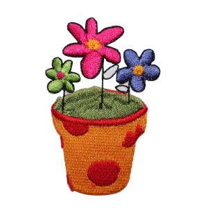 May include: A colorful embroidered patch of a potted plant with three flowers. The flowers are pink, blue, and green. The pot is orange with red polka dots.