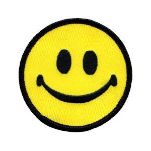 Peut inclure: Un patch jaune en forme de smiley avec un contour noir. Le smiley a deux yeux noirs et une bouche noire.