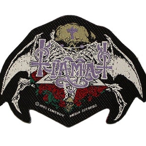 Könnte beinhalten: Ein schwarzer Aufnäher mit einem Skelett-Design, Flügeln und dem Wort "IAM" in Lila. Der Aufnäher enthält einen Totenkopf, Rosen und den Text "© 1995 CENTURY MEDIA RECORDS".