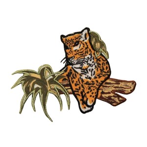May include: An embroidered patch depicting a brown and orange jaguar perched on a branch with green leaves. The jaguar has black spots and stripes.