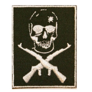 May include: White embroidered patch on a dark green background. The patch features a skull wearing sunglasses and a cap with a star on it. Two crossed rifles are below the skull.