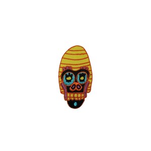 May include: Embroidered iron-on patch featuring a colorful skull with yellow and orange stripes, blue eyes, and a black nose.