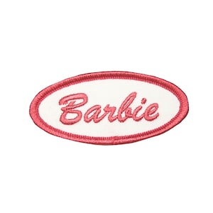 May include: A pink oval-shaped embroidered patch with the word "Barbie" in white cursive lettering.