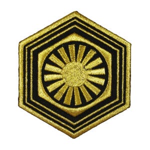 May include: A gold and black embroidered patch featuring the symbol of the First Order from Star Wars. The symbol is a hexagon with a sunburst design inside.