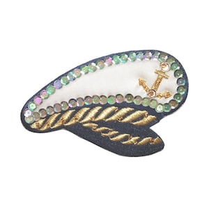 May include: A blue and white embroidered patch with a gold anchor and rope design. The patch is decorated with iridescent sequins.