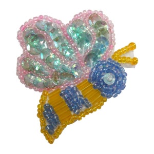 May include: A beaded bee applique with a pink and blue iridescent body and yellow wings. The bee has a blue and yellow striped abdomen.