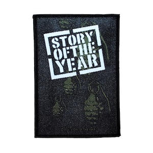 May include: Black and white patch with the text "STORY OF THE YEAR" in a white box with a black outline. The background is black with a green camouflage pattern.