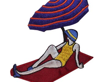 May include: An embroidered patch of a woman wearing a yellow swimsuit and a blue hat, relaxing on a red beach towel under a purple and orange striped beach umbrella.